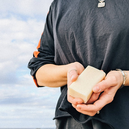 Two hands holding a bar of soap against themselves wearing a dark grey t-shirt