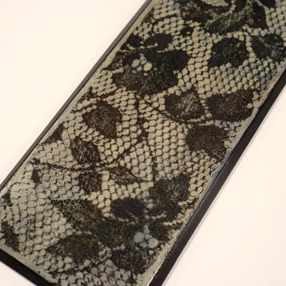 Close-up of a textured wall art with a lace pattern on a white background