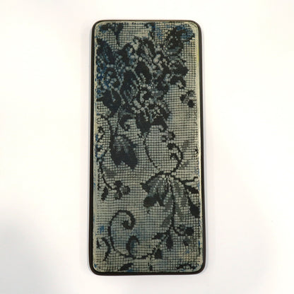 A piece of wall art of floral lace design imprinted into a blue background on a white background