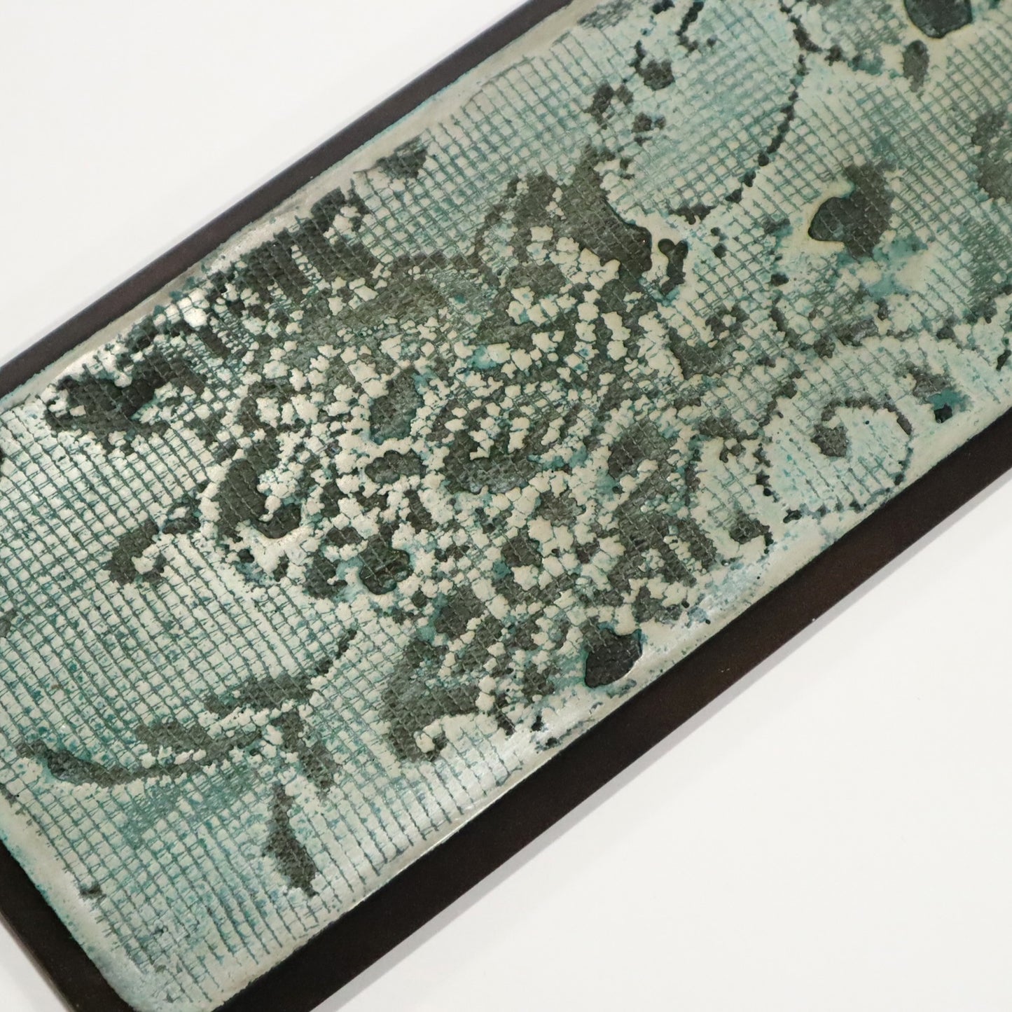 Teal and black patterned wall art on a white background