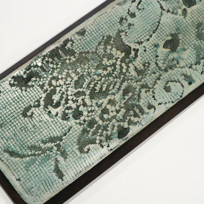 Teal and black patterned wall art on a white background