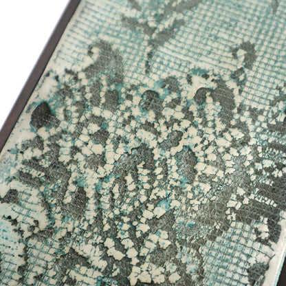 Close-up of a textured wall art with a lace pattern pattern in green