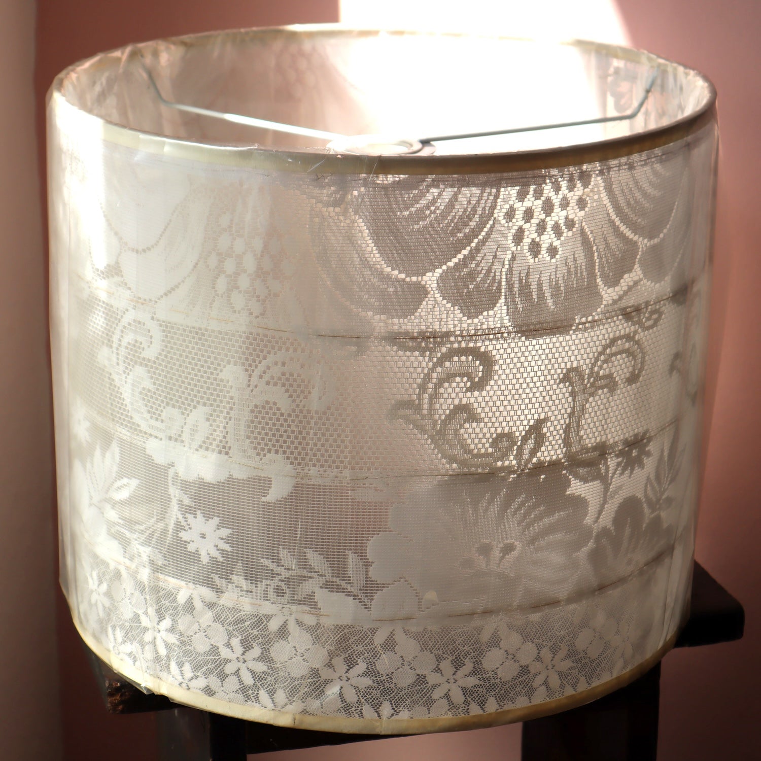 Lace-patterned lampshade against a pink wall