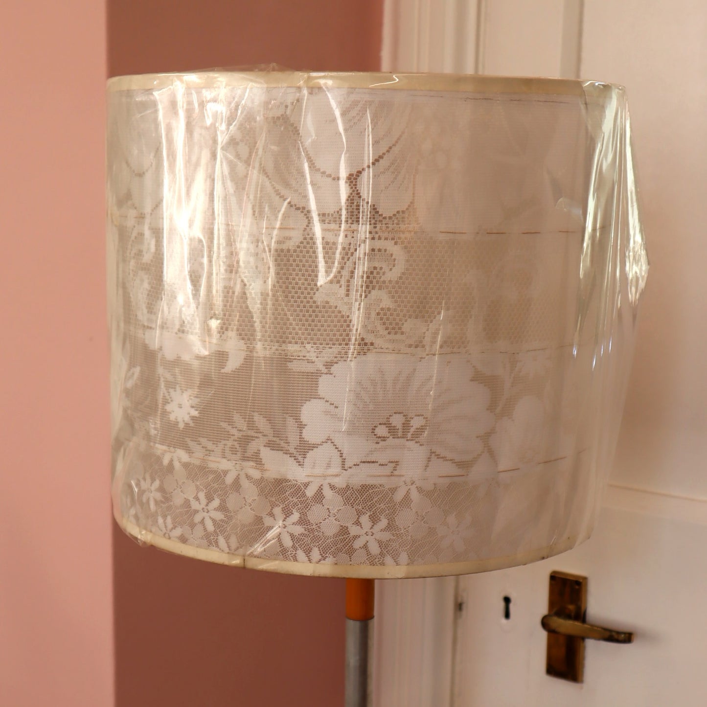 Lace lampshade on a stand with a pink wall background