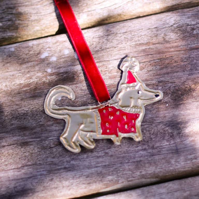 Decorative dog ornament with a red sweater and hat on a wooden surface