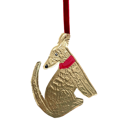 A tin embossing sitting dog ornament with a ribbon, featuring a hand-painted, unique enamel detail.