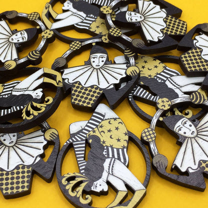 Multiple wooden pin brooches depicting a vintage style circus juggler, with a sombre look, laser-cut from sustainable walnut wood.