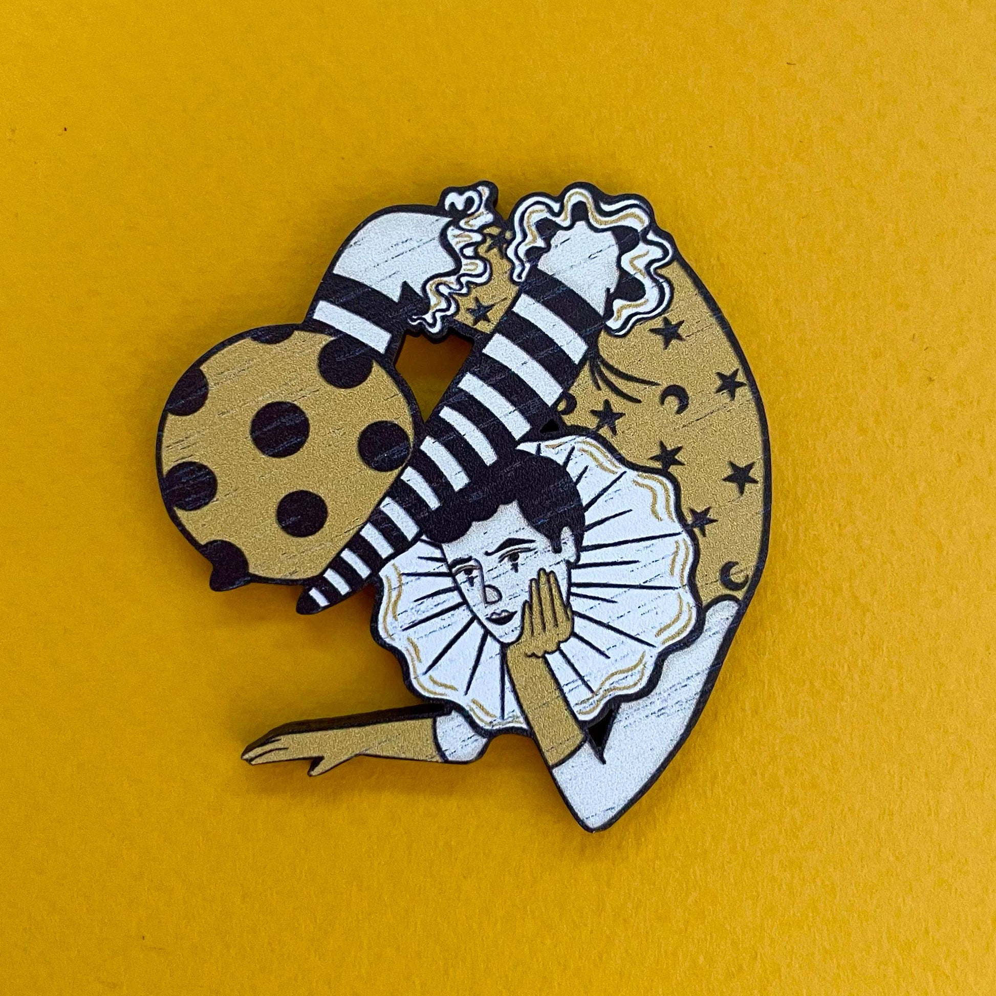 Pin with circus act design on a yellow background