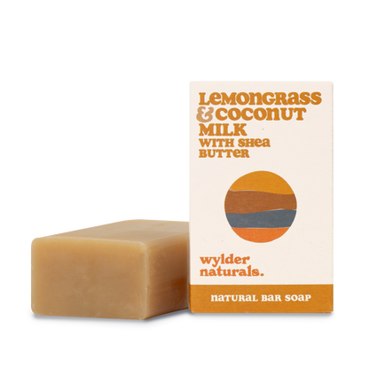 Bar soap sitting next to its packaging with branding labeled 'Lemongrass & Coconut Milk with Shea Butter' by wylder naturals