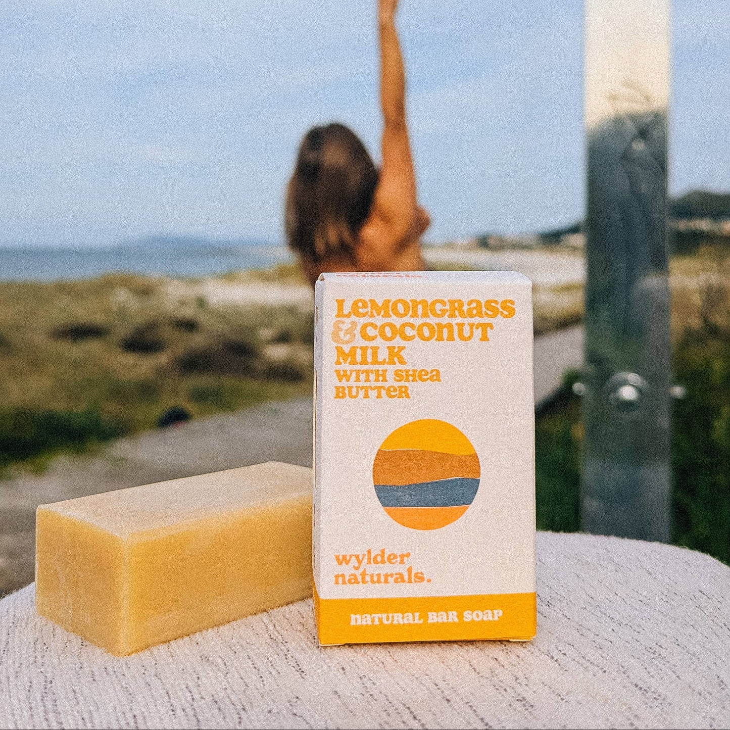 Yellow bar soap sat next to its box packaging by wylder naturals